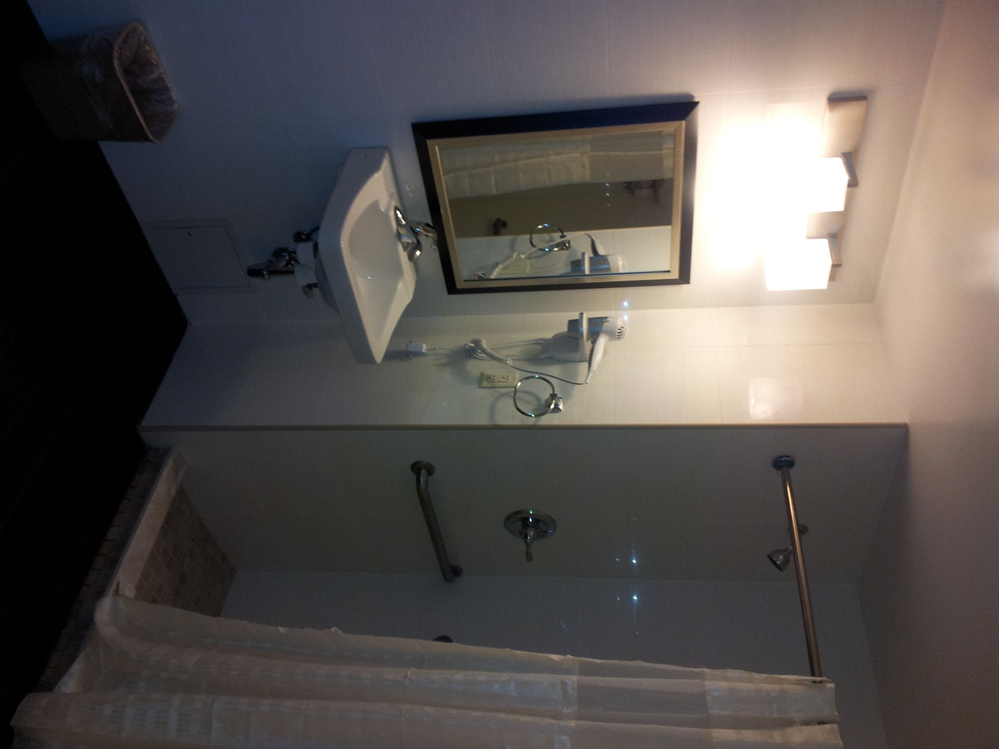 A bathroom with a sink, mirror, and shower.