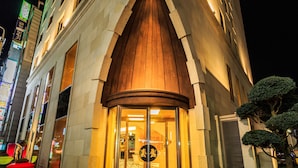 A hotel entrance with a large, illuminated archway and a circular emblem above the door. - Hotel Leo (Jeju City)
