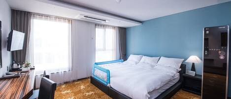Habitación de hotel con cama, escritorio, silla y televisor en la pared.