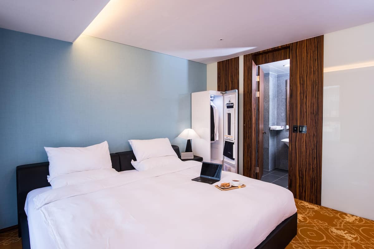 Ein Hotelzimmer mit einem Bett, einem Laptop und einem Tablett mit Speisen.