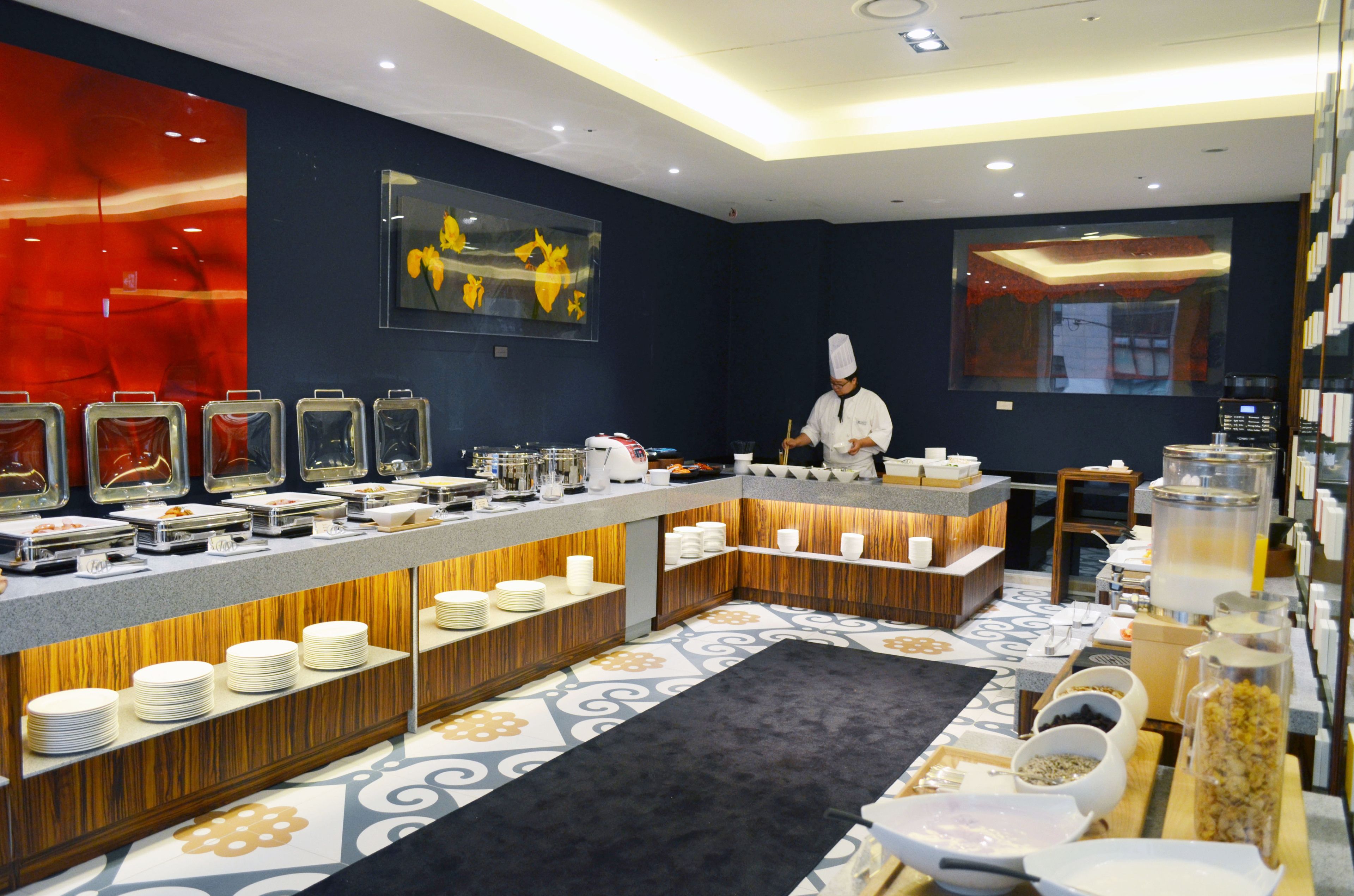 A buffet setup with various food stations, a chef preparing food, and a modern interior design.