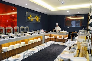 Montaje de bufé con diversas estaciones de comida, un chef preparando alimentos y un diseño de interiores moderno.