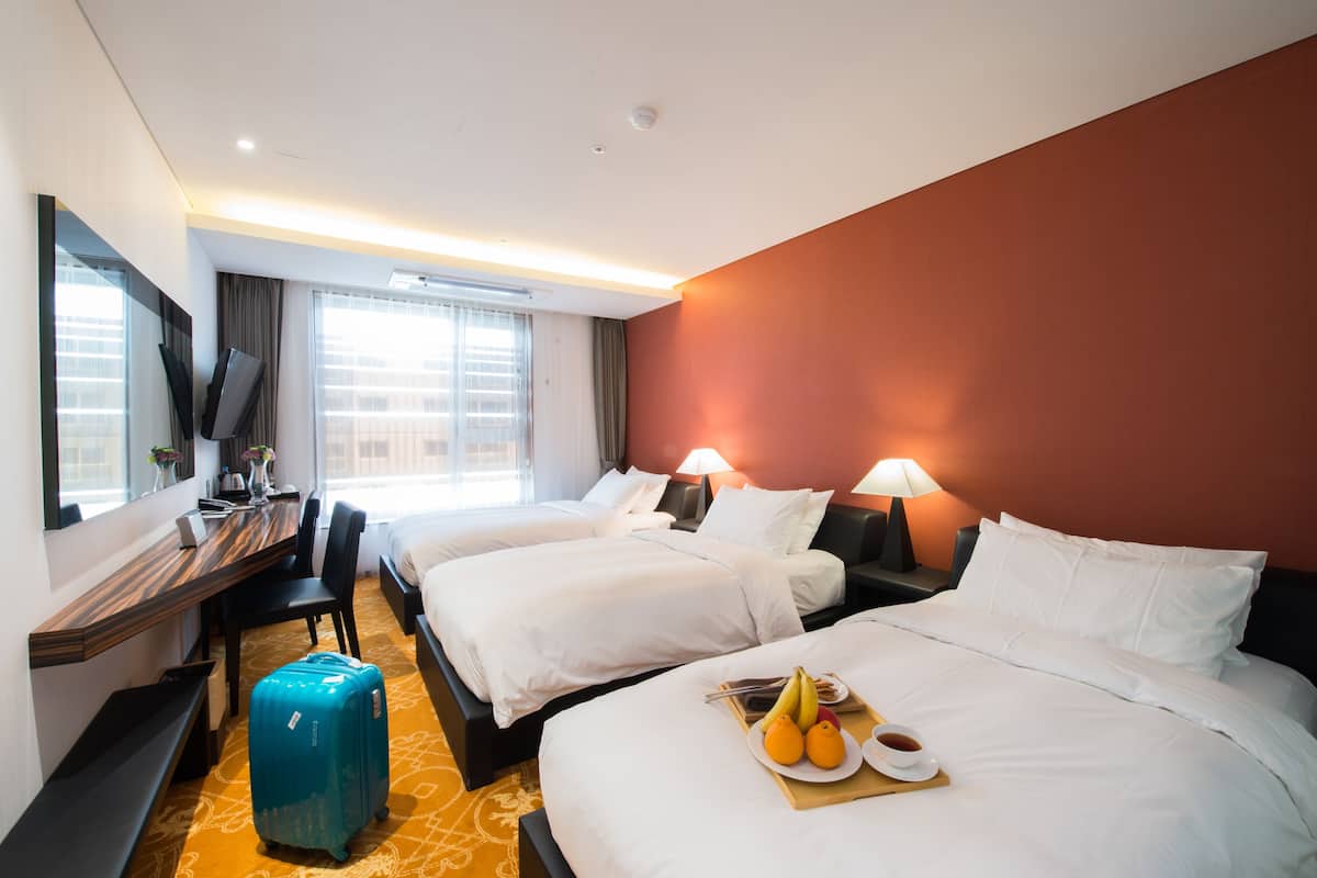 Ein Hotelzimmer mit zwei Betten, einem Schreibtisch und einem Koffer.