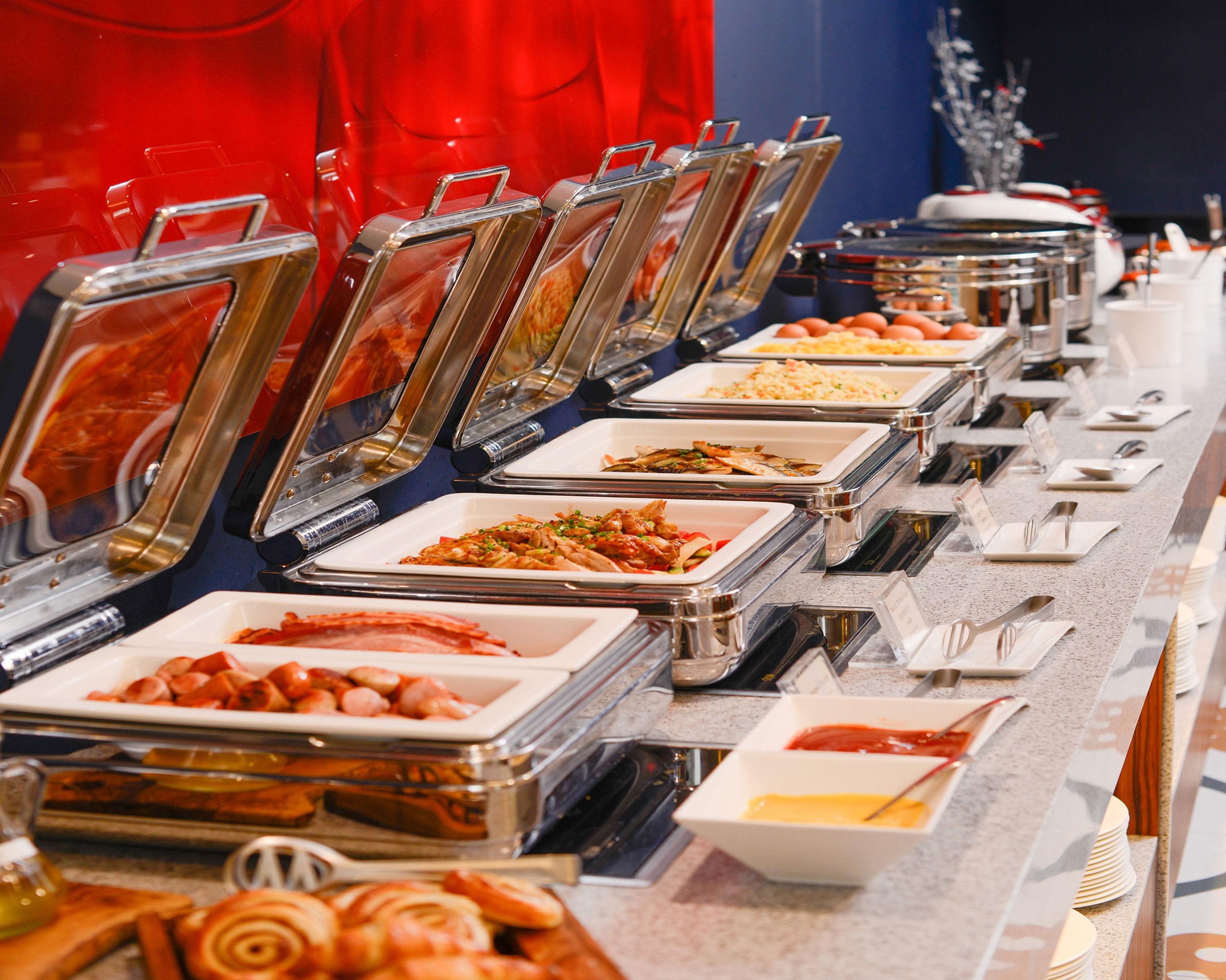 A buffet with various food options, including pasta, meats, and salads, arranged in clear serving dishes.