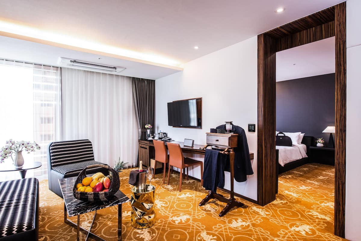 Ein Hotelzimmer mit Bett, Schreibtisch, Stuhl, Fernseher und Essecke mit Tisch und Stühlen.