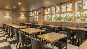 Ein Restaurant mit Schachbrettboden, Holztischen und schwarzen Stühlen.