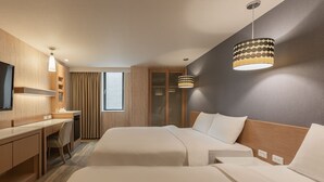 Ein Hotelzimmer mit zwei Betten, einem Schreibtisch, einem Sessel, einem Fernseher und einem großen Fenster mit Vorhängen.