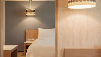 Habitación de hotel ordenada con cama, mesita de noche y lámpara colgante.