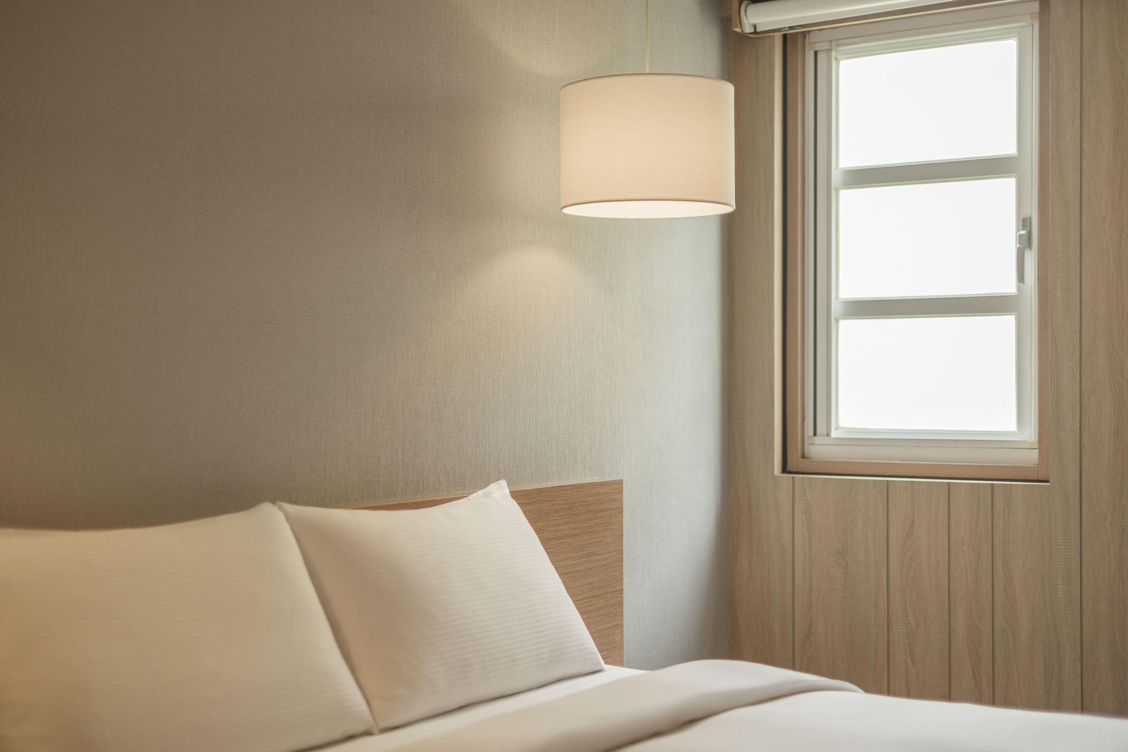 Ein Hotelzimmer mit Bett, Fenster und Wandlampe.