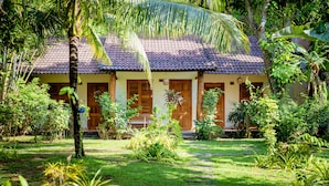 A traditional house with a tiled roof, surrounded by lush greenery and a stone pathway leading to the entrance. - La Mer Resort (Phu Quoc)