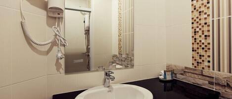 Un baño con un lavamanos blanco, un espejo y un secador de pelo en la pared.