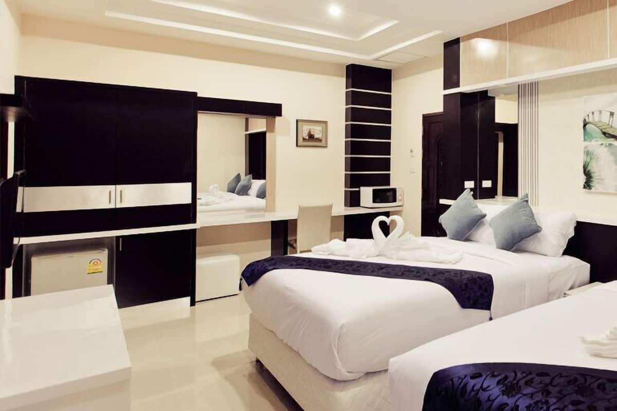 Una habitación de hotel moderna con dos camas, un escritorio, un armario y una pequeña cocina.