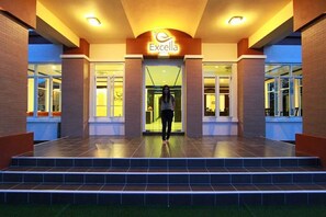 The entrance to Excella Hotel with a person walking up the steps. - Excella Hotel (Ubon Ratchathani)