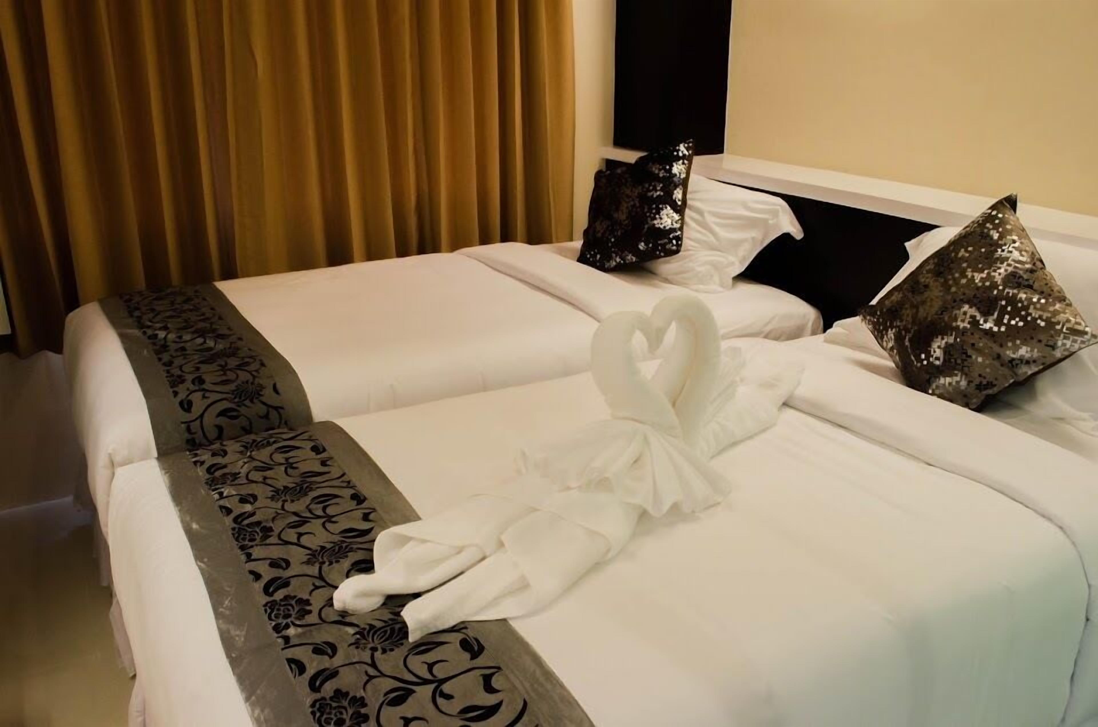 A hotel room with two beds, each with a white bedspread and decorative pillows.