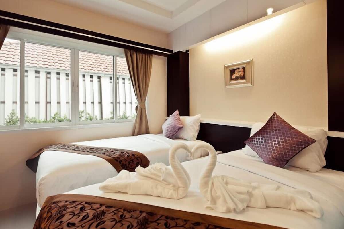 Habitación de hotel con dos camas, un ventanal con cortinas, un cuadro en la pared y un cabecero decorativo.
