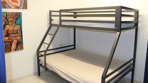 Uma cama de beliche com escada, parede branca e duas pinturas.