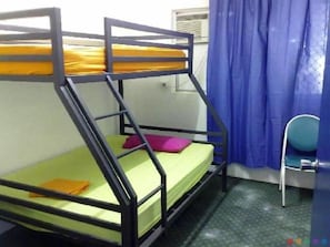Un letto a castello con un materasso giallo e uno verde, un cuscino rosa e una sedia blu.