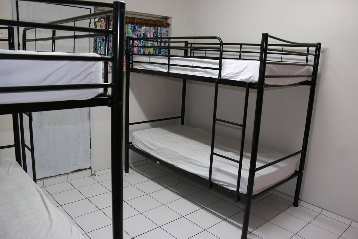 A bunk bed room with white bedding and tiled flooring.