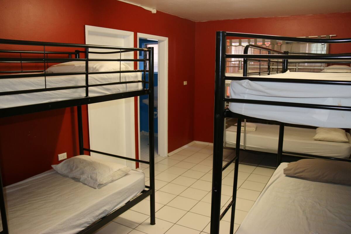 A dormitory room with bunk beds, a door, and a tiled floor.