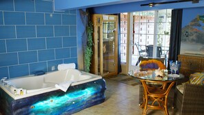Un baño con una bañera de temática galáctica, muebles de mimbre y vistas al exterior.