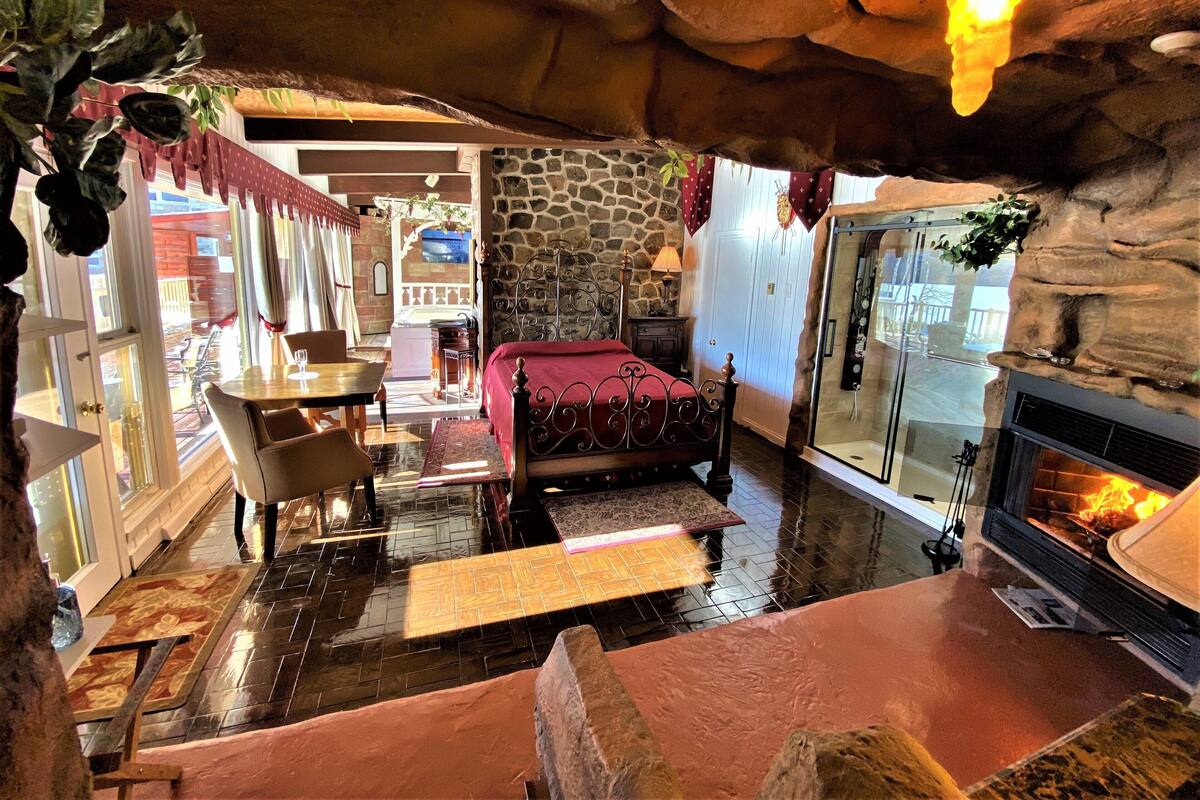 Una habitación acogedora con pared de piedra, cama, chimenea y zona de comedor con mesa y sillas.