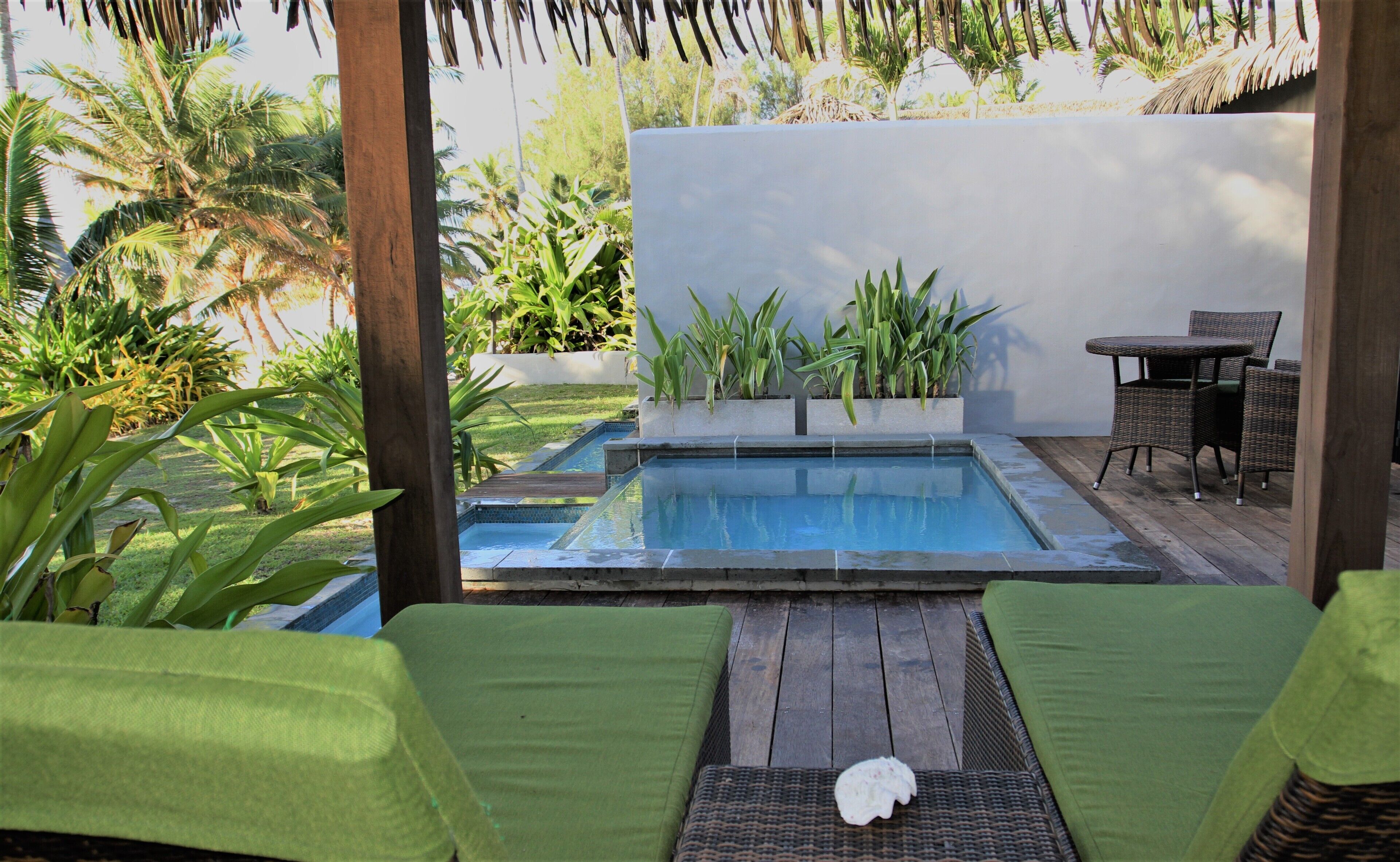 A pool area with lounge chairs, a table, and potted plants.