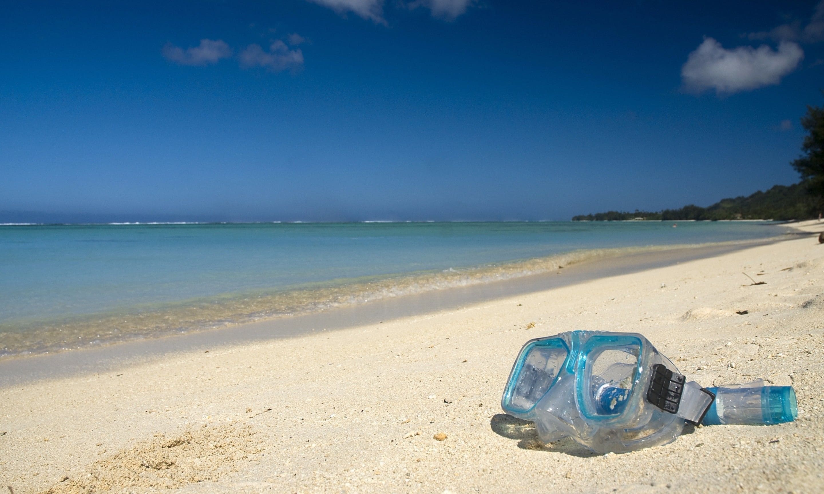 A clear beach with a plastic bottle lying on the sand.