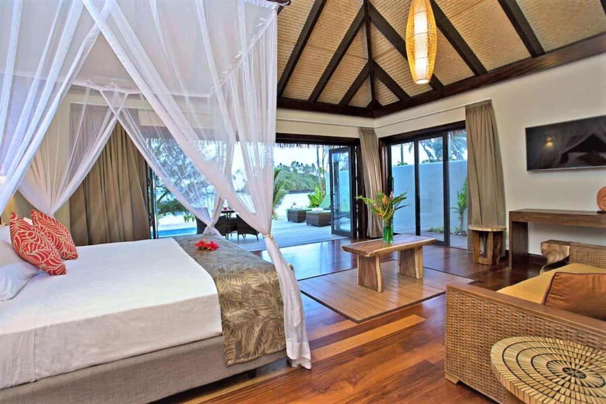 A bedroom with a canopy bed, a sofa, a coffee table, and a view of the outdoors.