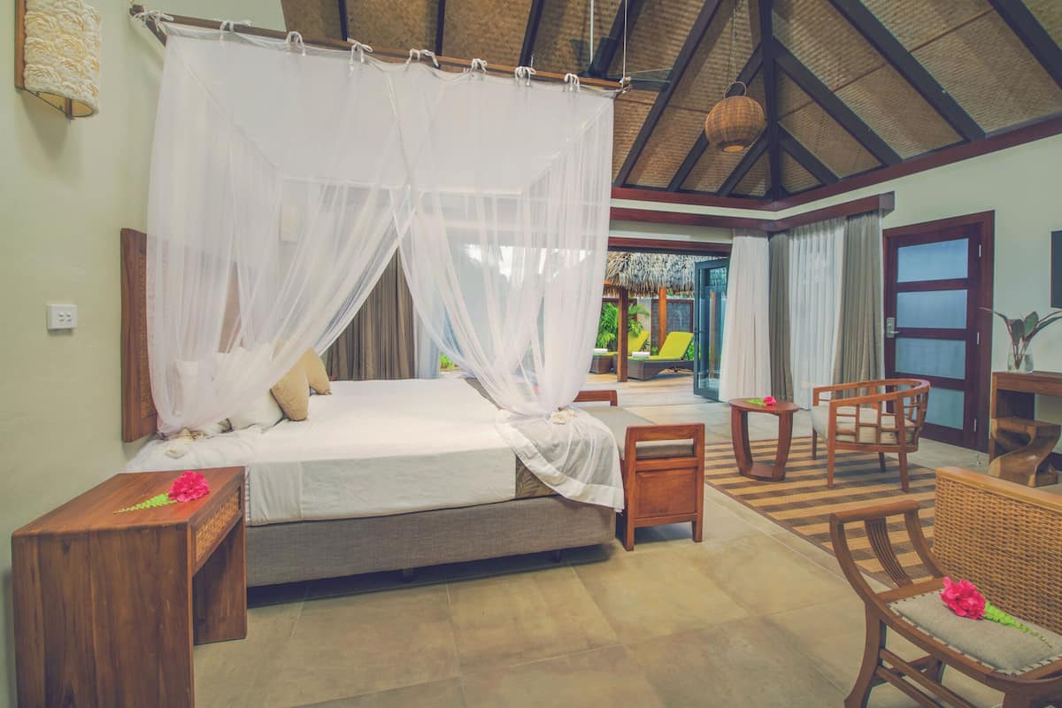 A bedroom with a canopy bed, wooden furniture, and a view of the outdoor area.
