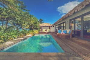 A poolside area with a clear pool, lounge chairs, and a thatched-roof structure. - Nautilus Resort (Rarotonga)
