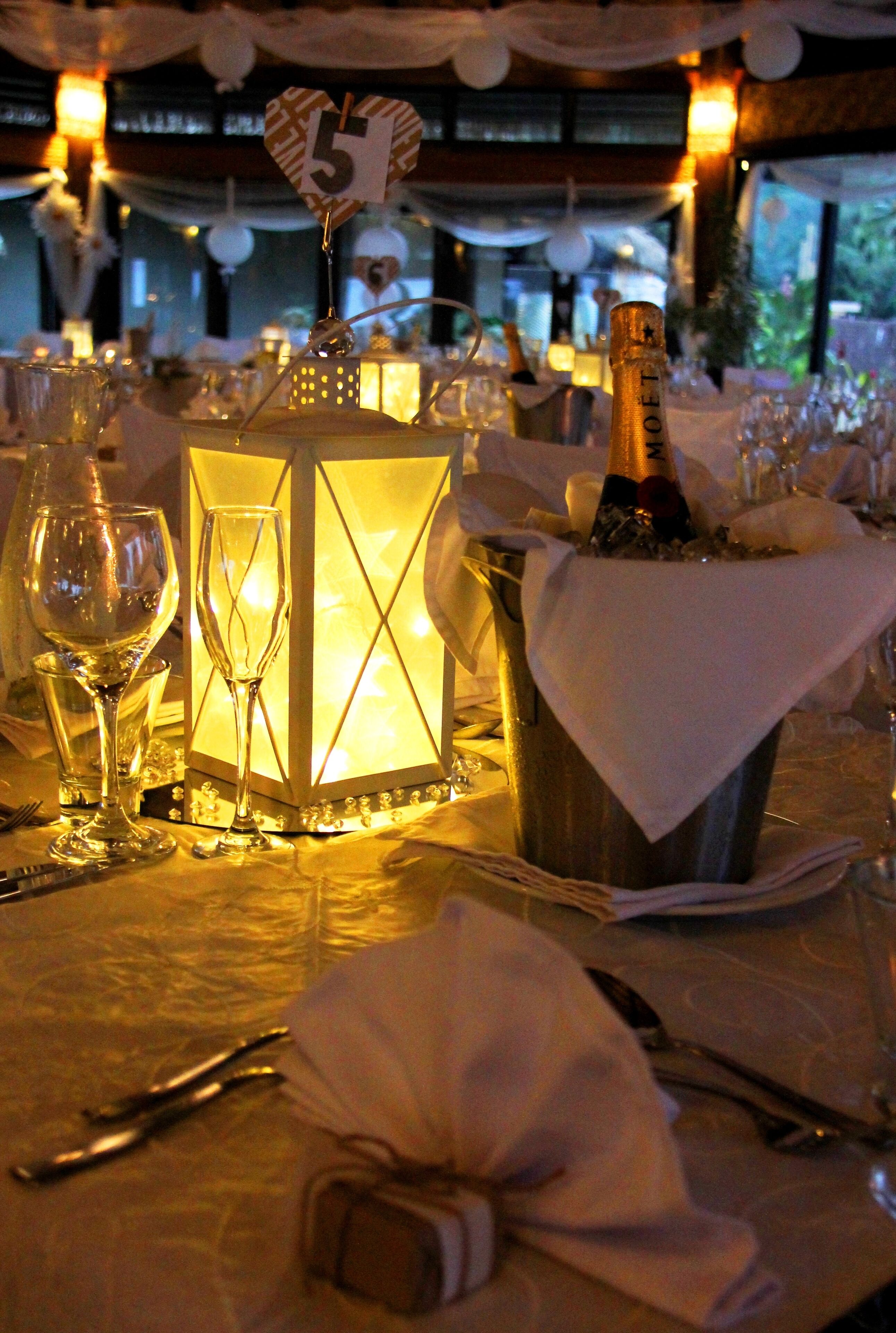 Een gedekte tafel voor een formeel evenement, met een brandende lantaarn, champagnefles en wijnglazen.