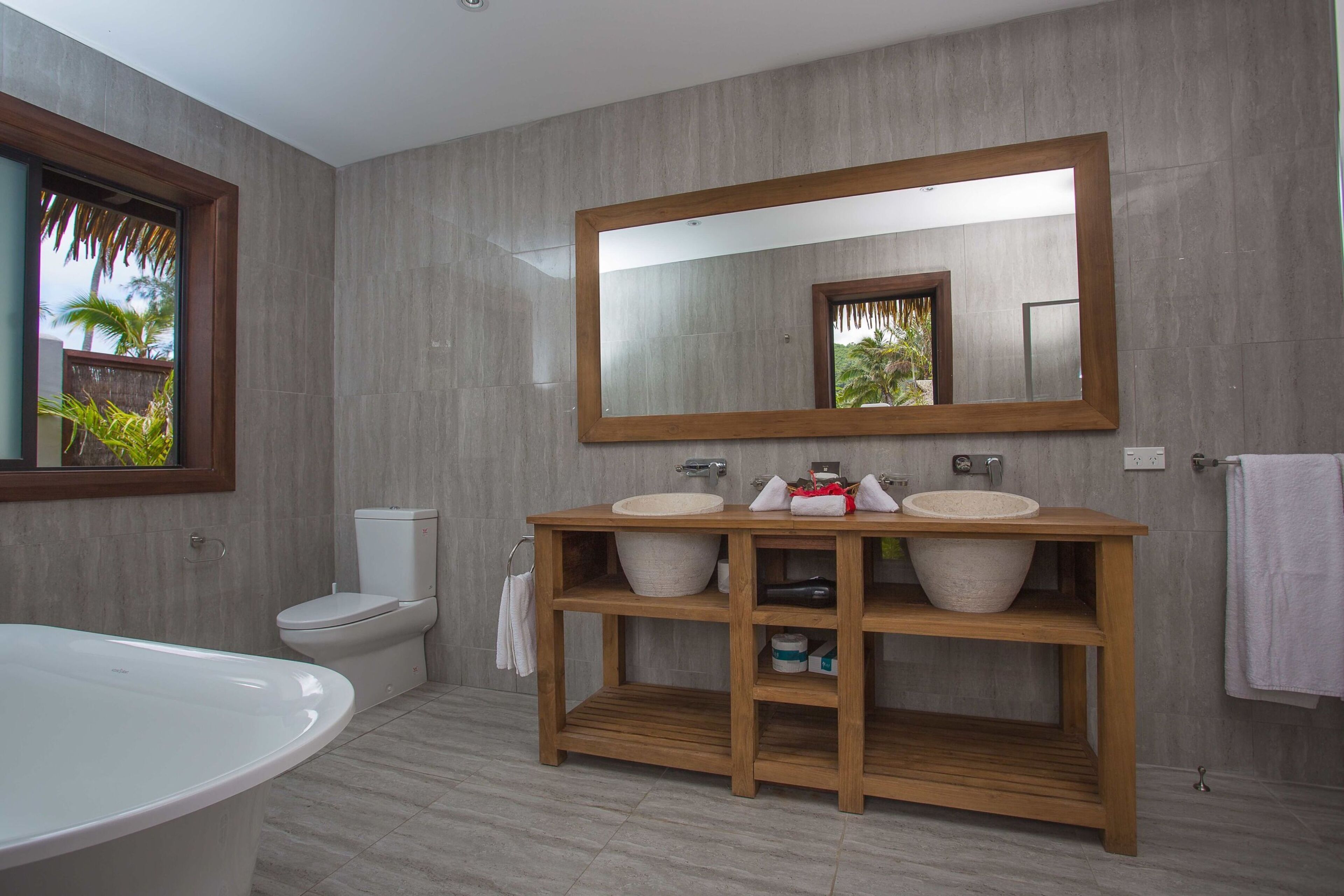 A modern bathroom with a freestanding bathtub, a double sink vanity, and a large mirror.