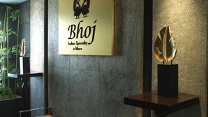A reception area with a bench, a wall-mounted sign, and a decorative sculpture. - Hotel Vrisa (Jaipur)