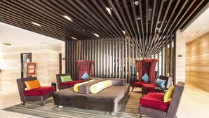 A modern lobby with a central seating area featuring sofas and armchairs, a striped carpet, and a ceiling with linear lighting fixtures. - Hotel Vrisa (Jaipur)
