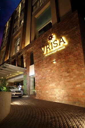 A hotel entrance with a brick facade and illuminated signage for 'VRISA HOTEL & BANQUET LOUNGE'. - Hotel Vrisa (Jaipur)