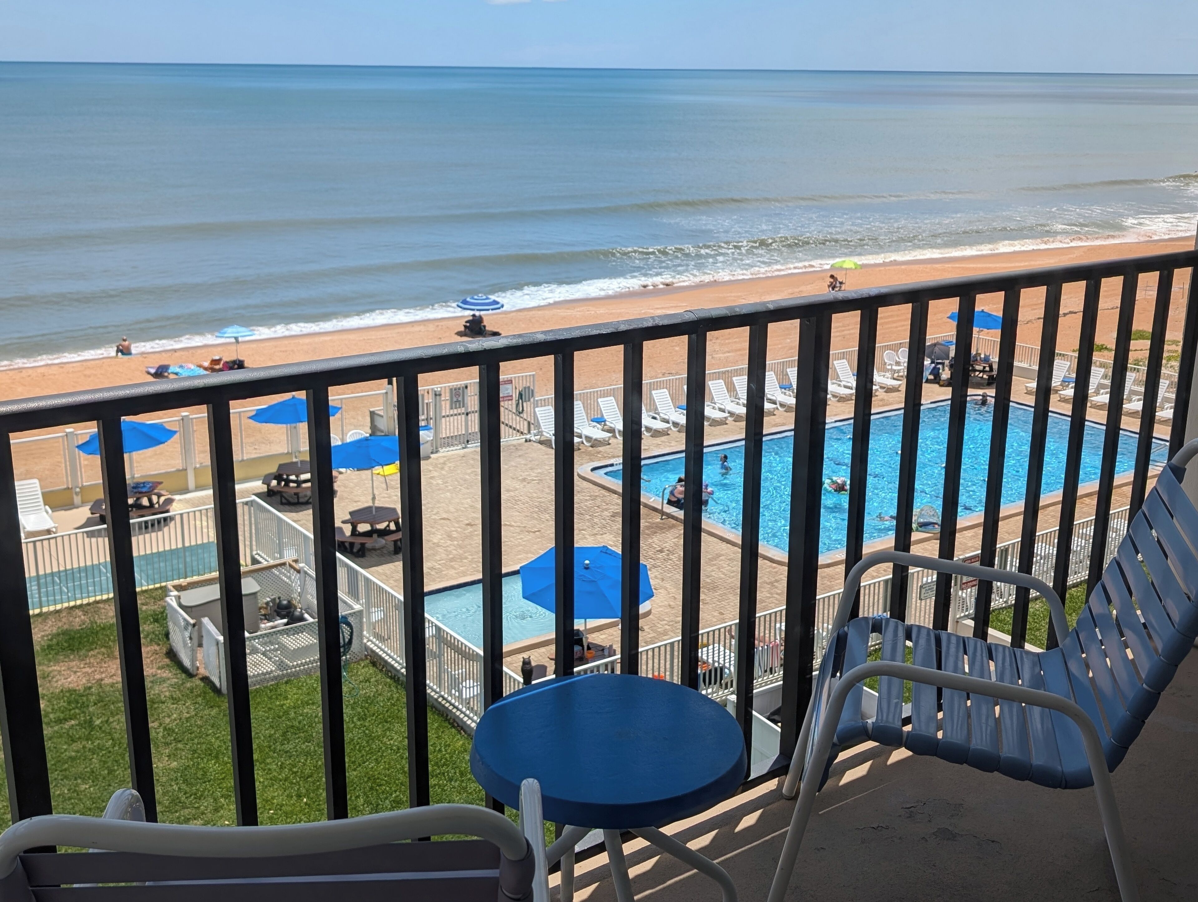 A balcony with a view of the beach and a swimming pool.