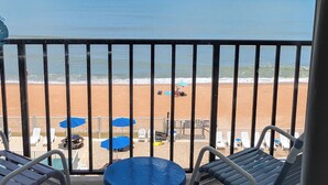 A balcony with a view of the beach, featuring lounge chairs and umbrellas. - Traders Inn Beach Club (Ormond Beach)