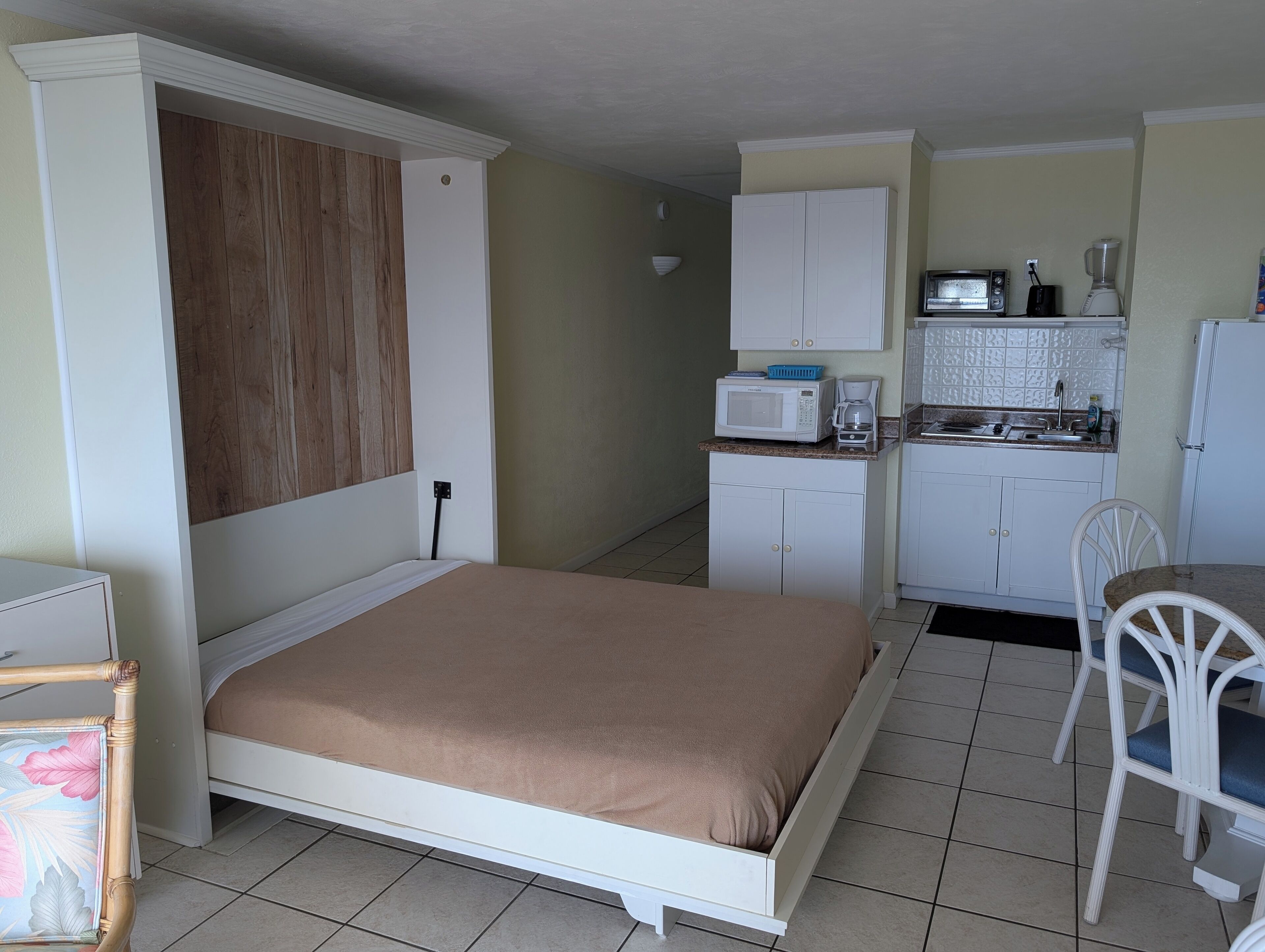 A compact room with a bed, kitchenette, and a small dining area.