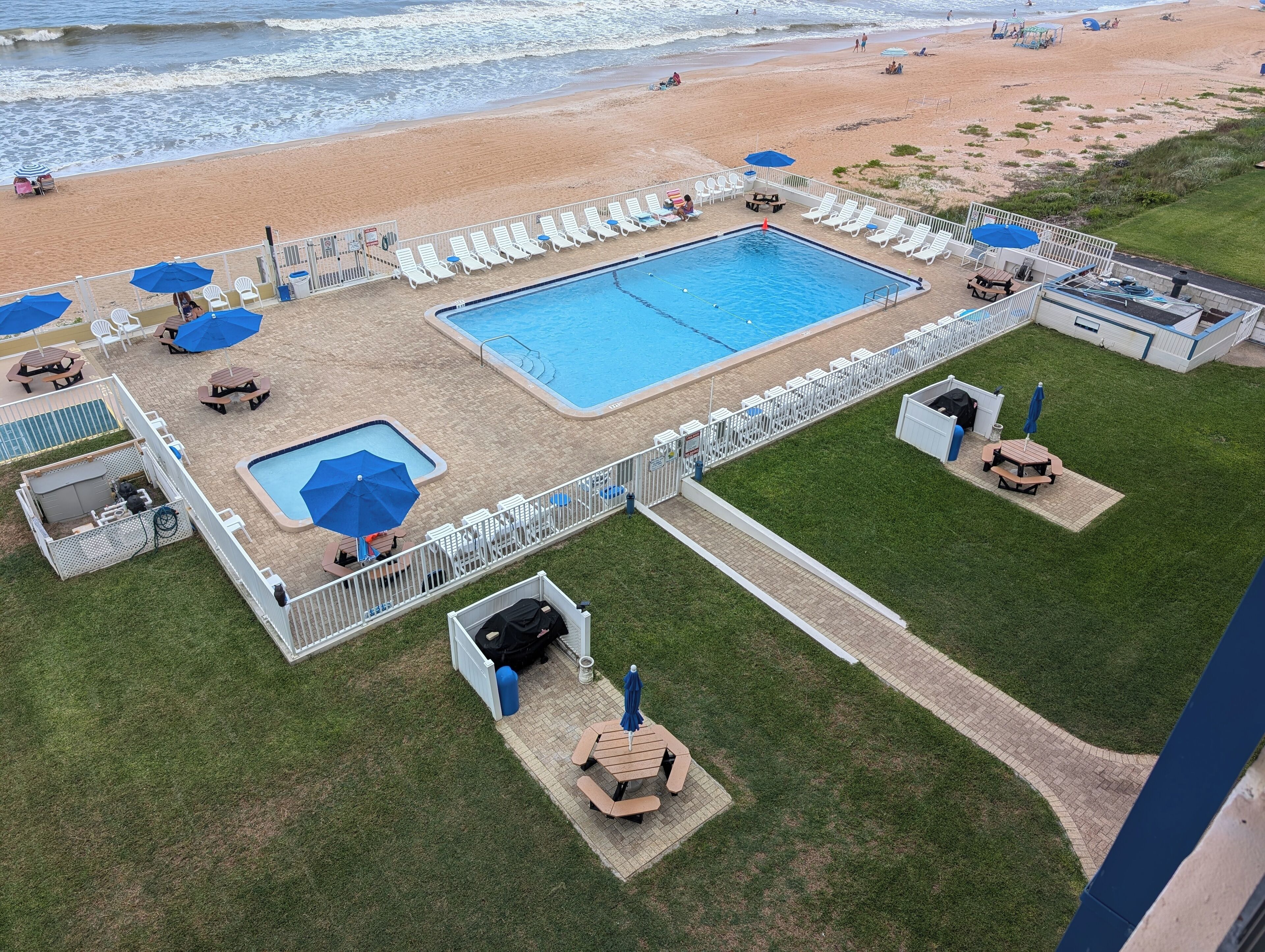 A pool area with a rectangular pool, lounge chairs, and umbrellas.