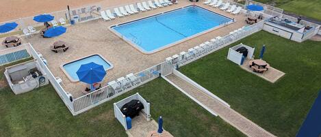 A pool area with a rectangular pool, lounge chairs, and umbrellas.