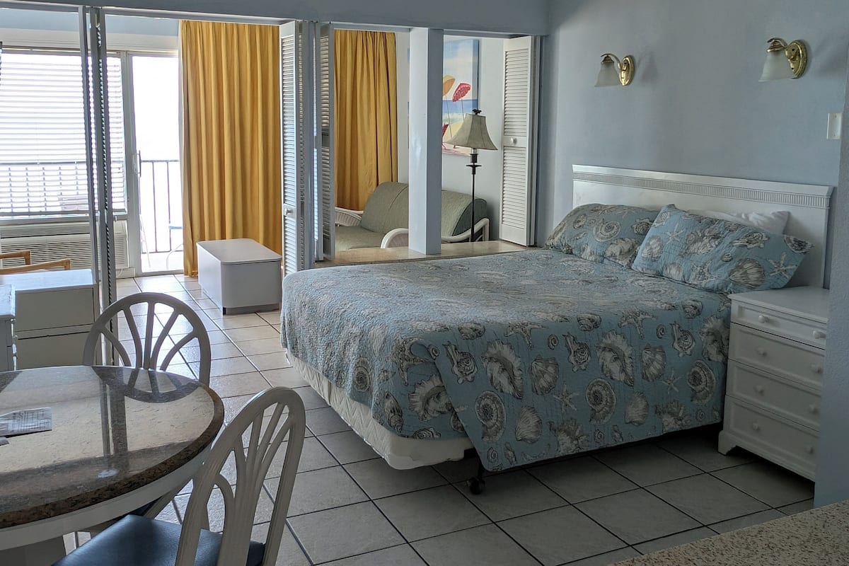 Una habitación de hotel con una cama, una silla, una mesa y vistas al exterior.