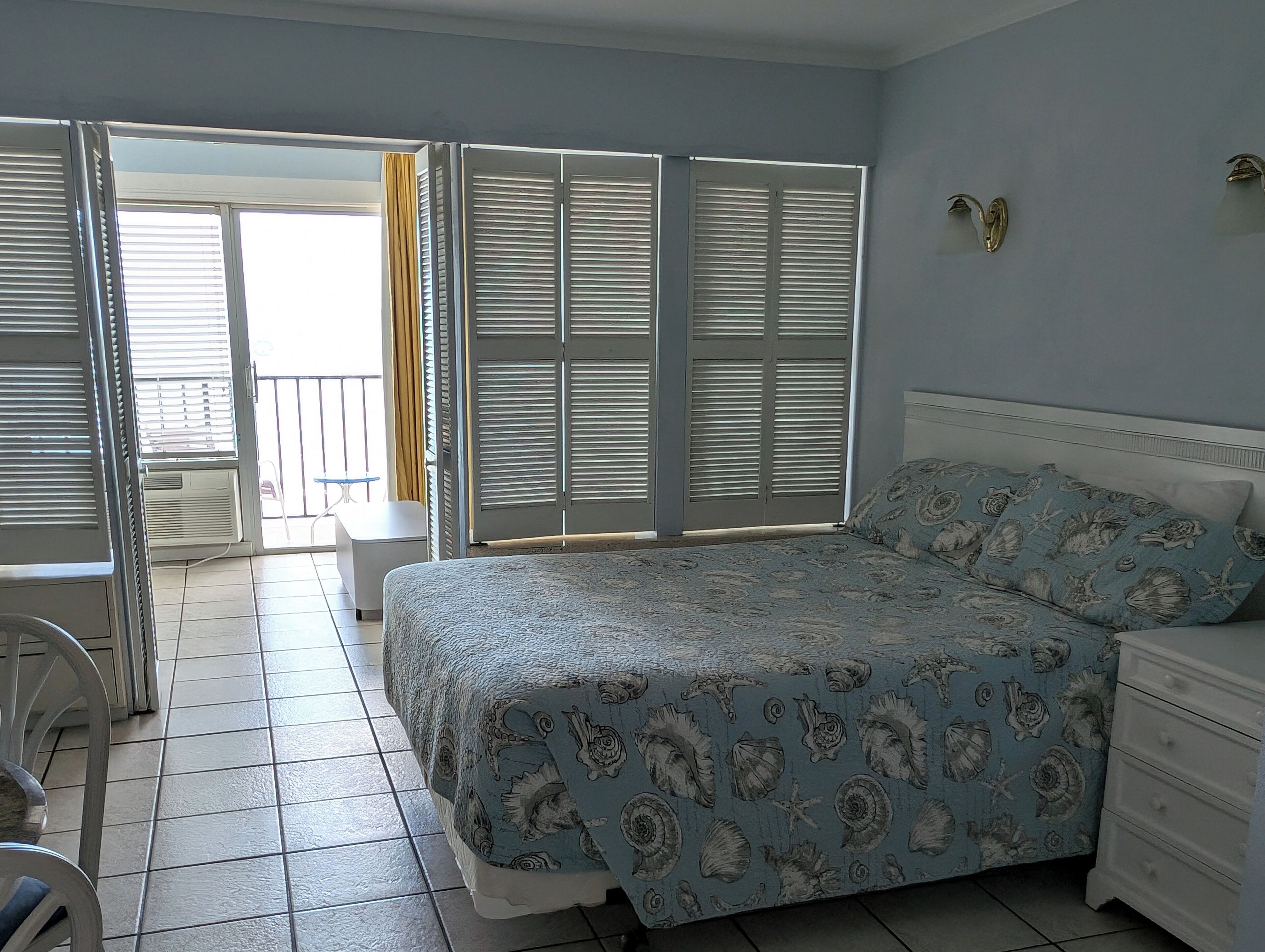 Ein Schlafzimmer mit Bett, Schminktisch und Blick auf den Balkon.