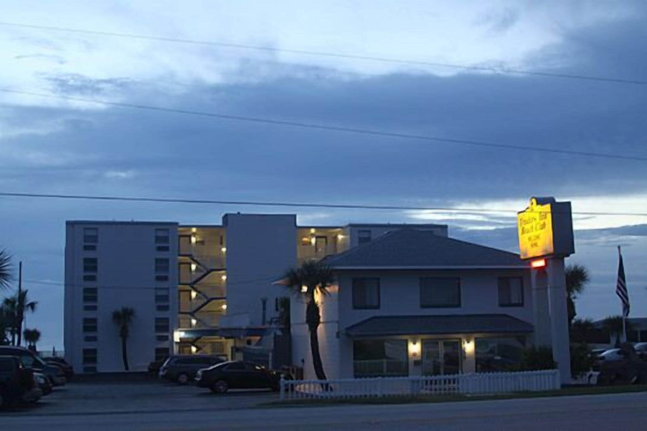 A motel with a two-story building, a parking lot, and a signboard.