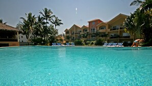 A clear swimming pool with lounge chairs and palm trees. - Agualina Kite Resort (Cabarete)