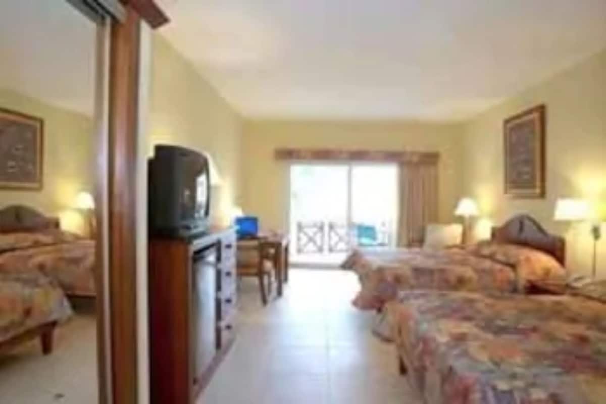 Een hotelkamer met twee bedden, een televisie, een bureau en een raam.