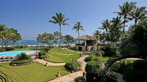 A resort with a swimming pool, palm trees, and a thatched-roof structure. - Agualina Kite Resort (Cabarete)