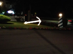 An arrow-shaped light installation stands out on a well-manicured lawn, pointing to the right.
