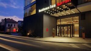 A modern hotel entrance with a glass facade, a prominent "Residence Inn Marriott" sign, and a well-lit entrance area.