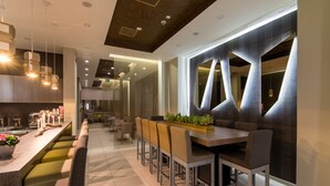 A modern dining area with a long counter, cushioned seating, and pendant lighting.
