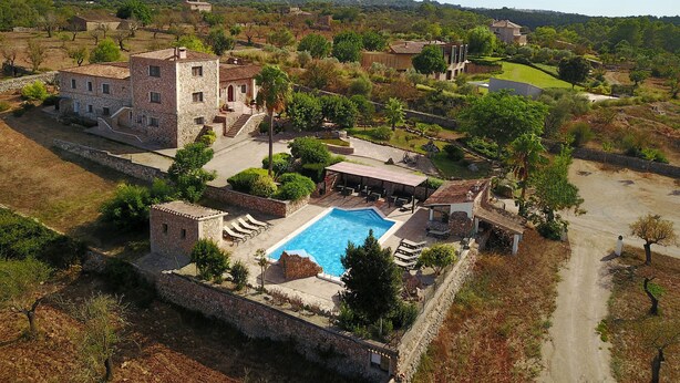 A large stone building with a swimming pool, surrounded by trees and a hilly landscape. - Agroturismo Son Ginebró (Inca)